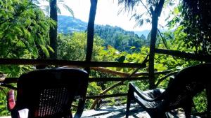 zwei Personen, die auf einer Veranda mit Bergblick sitzen in der Unterkunft Green Jungle " Cool view" in Ella