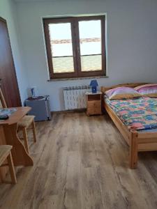 1 dormitorio con cama, mesa y ventana en Pokoje Goscinne TOMASZ, en Międzywodzie