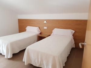 two beds in a hotel room with white sheets at Apartamentos Canada 1 in Raxo