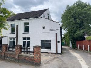 a white house with a fence in front of it at Silk Apartments Spondon in Derby