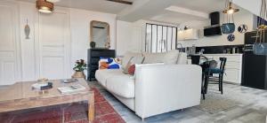 een woonkamer met een witte bank en een tafel bij Bleu - Éden - appartement moderne en hypercentre in Vichy