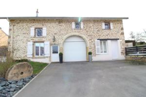 uma casa de tijolos com uma porta de garagem branca em Gîte La Belle Vosgienne em Aydoilles