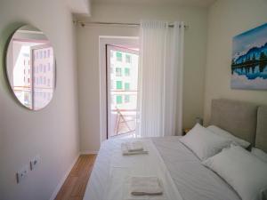 a bedroom with a bed with a mirror and a window at Modern Apt in Mangalem21 Complex WiFi,AC in Tirana