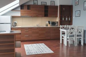 ブワディスワボボにあるMieszkanie Słoneczne Reja 2Bのキッチン(木製キャビネット、白いテーブルと椅子付)