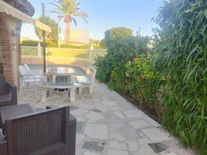 een patio met een tafel, stoelen en planten bij Estudios privados en Villa con piscina privada in Els Poblets