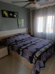 een slaapkamer met een bed met een blauw dekbed en een raam bij Estudios privados en Villa con piscina privada in Els Poblets