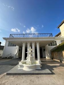 a white building with a white fountain in front of it at Indra Manel Family Holiday Resort Kandy in Kandy