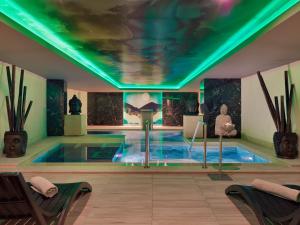 einen Pool in einem Zimmer mit einer Decke mit grüner Beleuchtung in der Unterkunft Gran Oasis Resort in Playa de las Americas