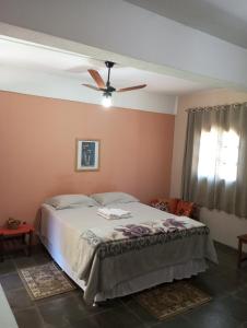 a bedroom with a bed and a ceiling fan at Pousada Nasa in São Bento do Sapucaí