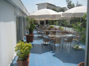 un patio al aire libre con mesas, sillas y sombrillas en Albergo dei Pini en Andria