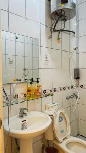 W łazience znajduje się umywalka, toaleta i lustro. w obiekcie Wujuwusu w mieście Jincheng