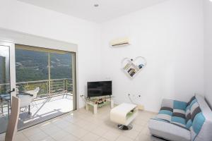 salon z kanapą i telewizorem oraz balkonem w obiekcie Villa Faneromeni w mieście Sivota