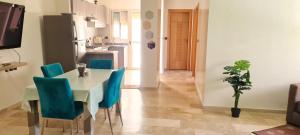 a dining room with a table and blue chairs at Bel appartement Savannah Beach in Sidi Rahal