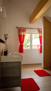 ein Badezimmer mit einem Waschbecken und ein Fenster mit roten Vorhängen in der Unterkunft Ferienwohnung Mayer in Schluchsee