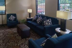 Comfort Inn Marion near Downtown & Blue Ridge PKWY في ماريون: غرفة معيشة مع الأرائك الزرقاء والطاولات والنوافذ