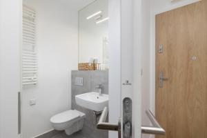 a white bathroom with a toilet and a sink at Saska Blu Studio Apartments Podgórze by Renters in Krakow