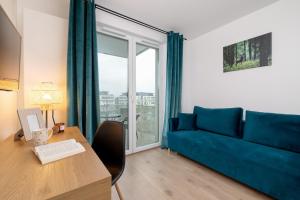 a living room with a blue couch and a table with a laptop at Saska Blu Studio Apartments Podgórze by Renters in Krakow