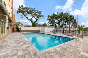 a swimming pool with chairs and a fence at Comfort Suites St Augustine Historic District Area in Saint Augustine