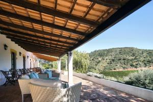 a patio with a wooden roof with chairs and tables at Vale Fuzeiros Nature Guest House in Vale Fuzeiros