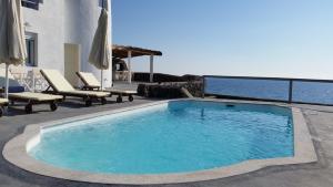 a swimming pool on a patio with chairs and the ocean at Abelomilos Exclusive Villa in Imerovigli