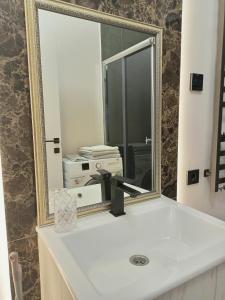 baño con espejo sobre un lavabo blanco en Apartment in Bozdosh estate en Úzhgorod