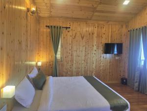 a bedroom with a bed with wooden walls and a television at LaSerene The Cottage in Nainital