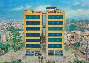 a yellow building in the middle of a city at The Rich Hotel & Apartments in Lahore