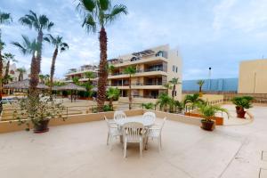 a patio with a table and chairs and palm trees at La Costa Beautiful Golf Villa in San José del Cabo