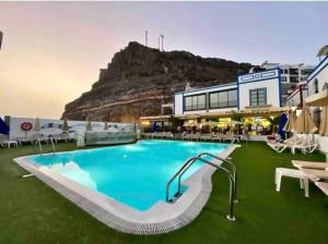 a resort with a swimming pool with a mountain in the background at Casa Apolo in Mogán