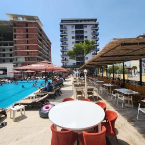 a pool with tables and chairs and a white table at Low Cost Hotel Kosova in Shëngjin