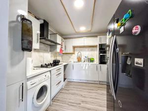 a kitchen with white cabinets and a refrigerator at Spacious Double Bedroom in Shooters Hill in London