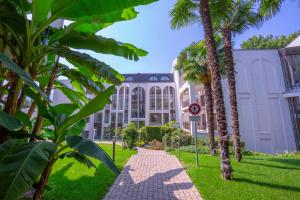 a building with palm trees and a sidewalk at Maraini Elegante Apartment with Jacuzzi & Balcony - Happy Rentals in Lugano