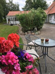 a patio with a table and chairs and flowers at Stunning Romantic Cabin close to Baltic see in Idestrup