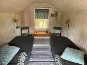 a bedroom with two beds and a window with two chairs at Stunning Romantic Cabin close to Baltic see in Idestrup