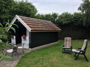 a black and white shed with two chairs and a table at Stunning Romantic Cabin close to Baltic see in Idestrup