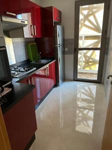 a kitchen with red cabinets and a refrigerator at Les perles de mimosa Mohammédia in Mohammedia