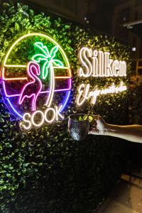 a woman holding a plant in front of a neon sign at Silken Atlántida Santa Cruz in Santa Cruz de Tenerife