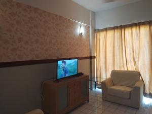 een woonkamer met een tv en een stoel bij Shahmi Seaview Apartment (North) in Port Dickson