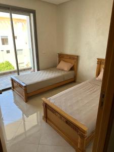 Dos camas en una habitación con ventana. en Les perles de mimosa Mohammédia, en Mohammedia