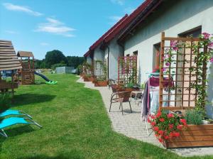 a patio with a table and chairs and flowers at Domki Afrodyta in Jarosławiec