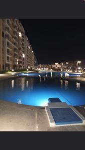 a large swimming pool at night with a city at Porto golf marina in El Alamein