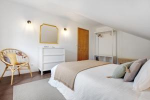 a white bedroom with a bed and a chair at Casa da Olides - Studio in Santana