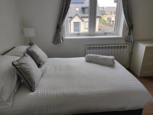 a white bed in a bedroom with a window at The Station Hotel in Alness