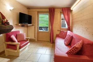 ein Wohnzimmer mit einem roten Sofa und einem TV in der Unterkunft Baita dei ski app 1 in Livigno
