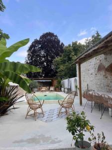 a patio with a table and chairs and a swimming pool at Maison Hortense 4 étoiles piscine chauffée et sauna in Buxeuil +72 photos