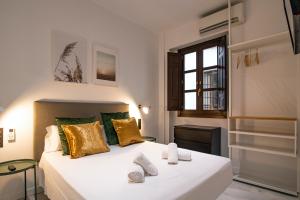 格拉纳达Granadi Apartamentos的卧室配有白色床和黄色及绿色枕头