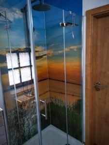 ein Badezimmer mit einer Dusche und einem Bild eines Sonnenuntergangs in der Unterkunft Ferienhaus Bultperle in Hüde