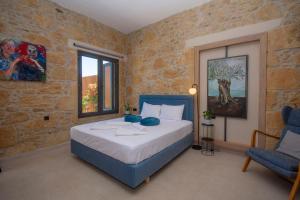 a bedroom with a large bed and a blue chair at Cavos Luxury Apartments in Kissamos