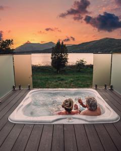 two people in a jacuzzi tub with a view of a lake at SeaBeds - Luxury Lookouts with Hot Tubs in Glencoe