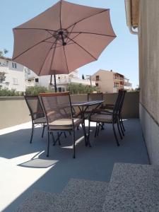 una mesa y sillas con una sombrilla en el balcón en Bošana Beach Apartment Biograd, en Biograd na Moru
